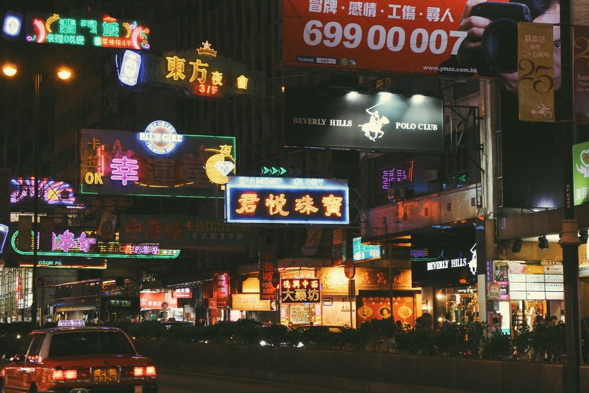 Neon shop signs adhered to buildings glowing at night